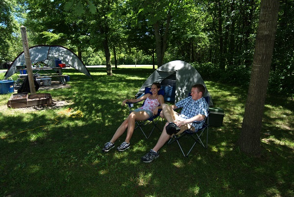 a couple sitting in front of their tent in the campground