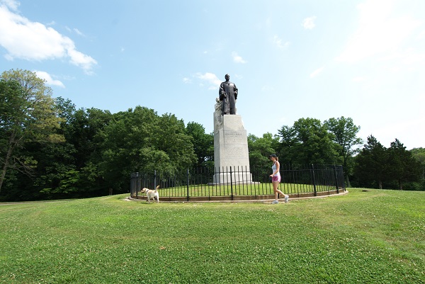 girl walking her dog around the statue of Edmund Babler