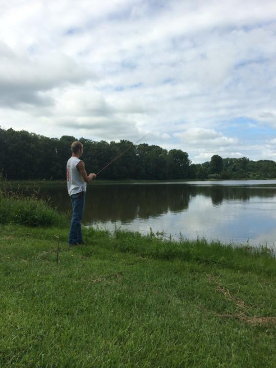 man fishing from the shore of the lake