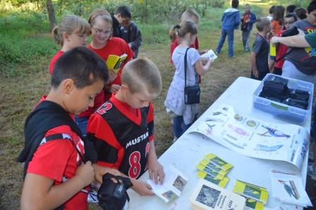a group of kids looks at brochures on a table
