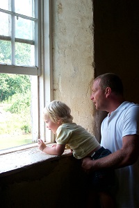 a man holds a small child so that he can see out the window of the mill