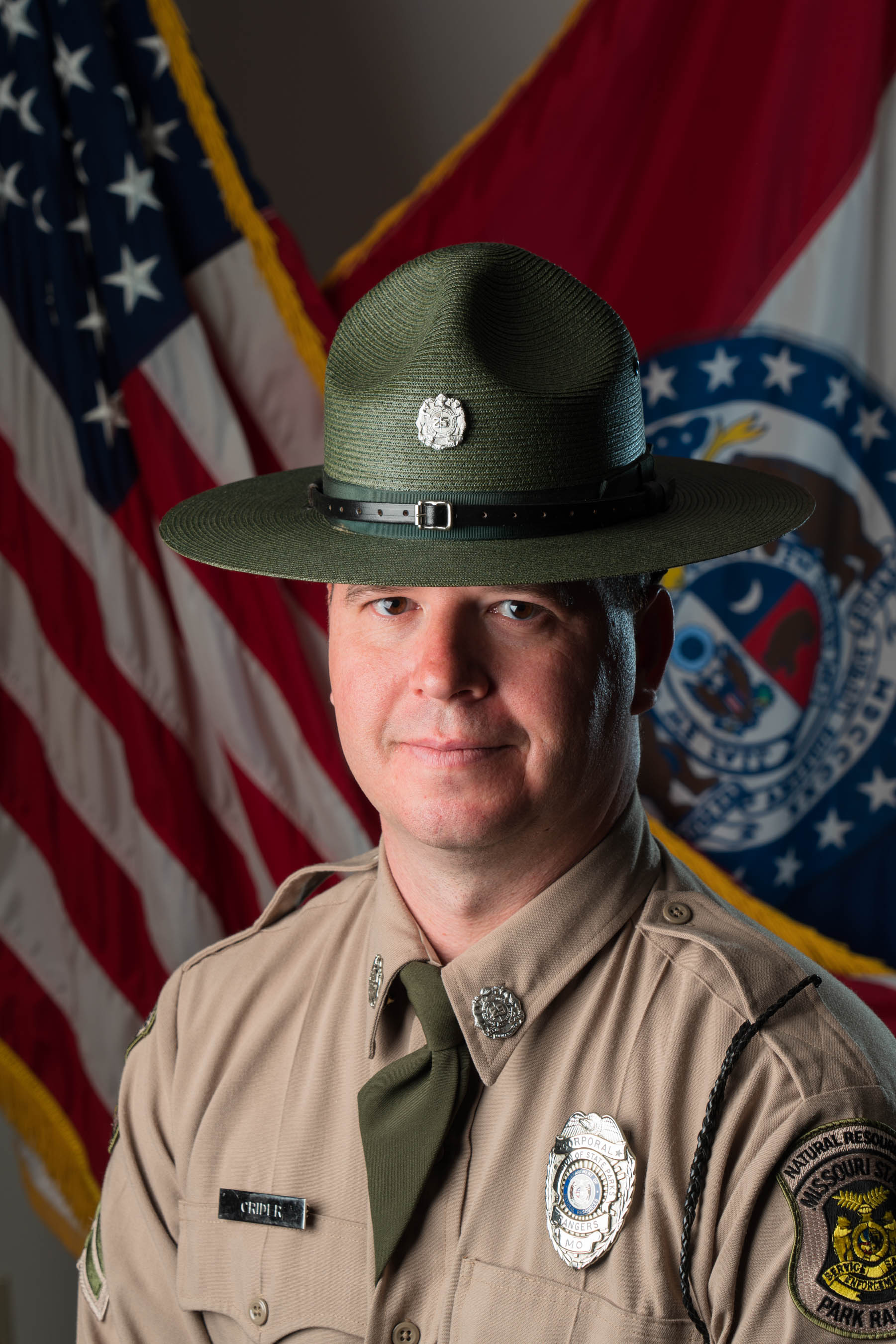 Chris Crider in hat and uniform with U.S. and Missouri flags and background