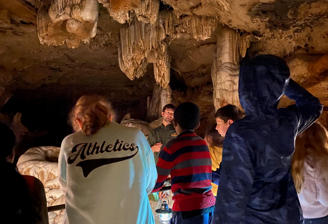 A guide speaks to students inside a cave