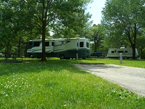 a long white camper backed into a shaded campsite