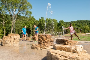 kids playing in water squirting from rocks 