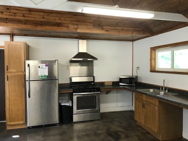 Cabinets, refrigerator, trash can, stove, toaster and skins inside the enclosed shelter