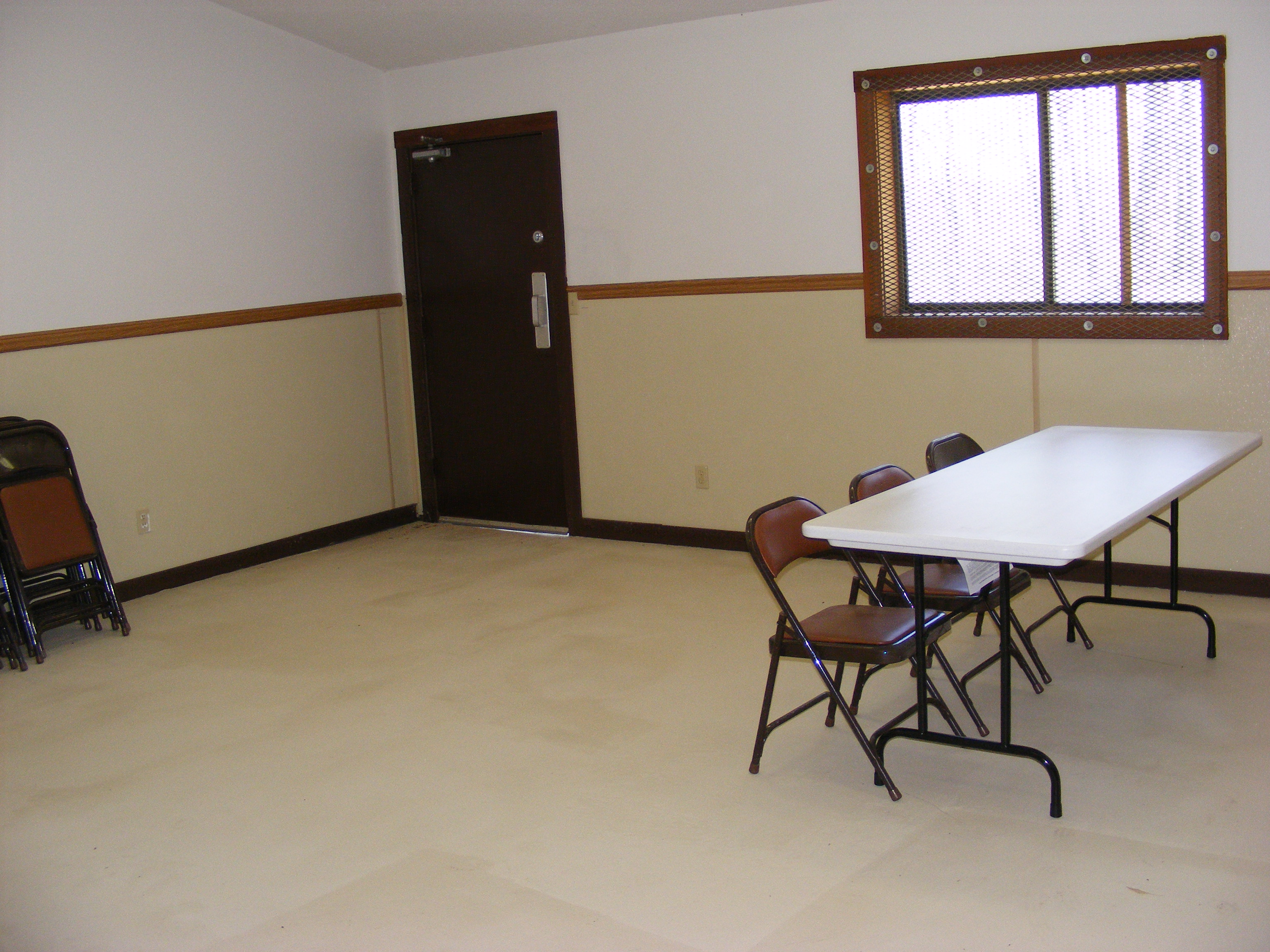 View of folding chairs and a table near a window inside the enclosed shelter