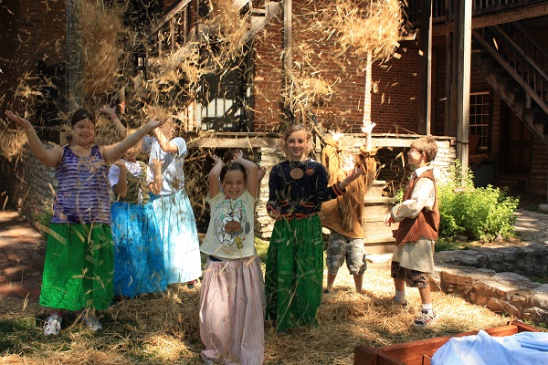 children in period attire playing in straw