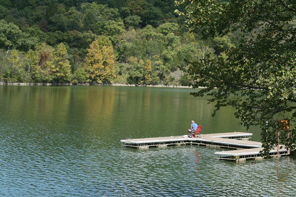 someone sitting in a lawn chair fishing off a dock