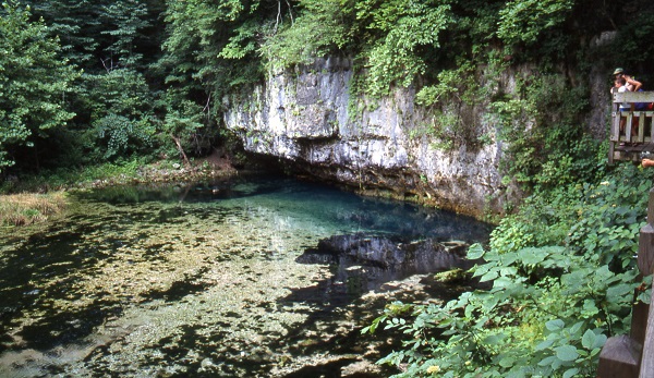 the blue water of the spring beneath a overhanging rock bluff