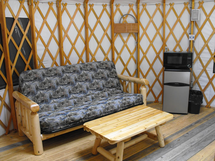 Futon and mini fridge and microwave inside the yurt