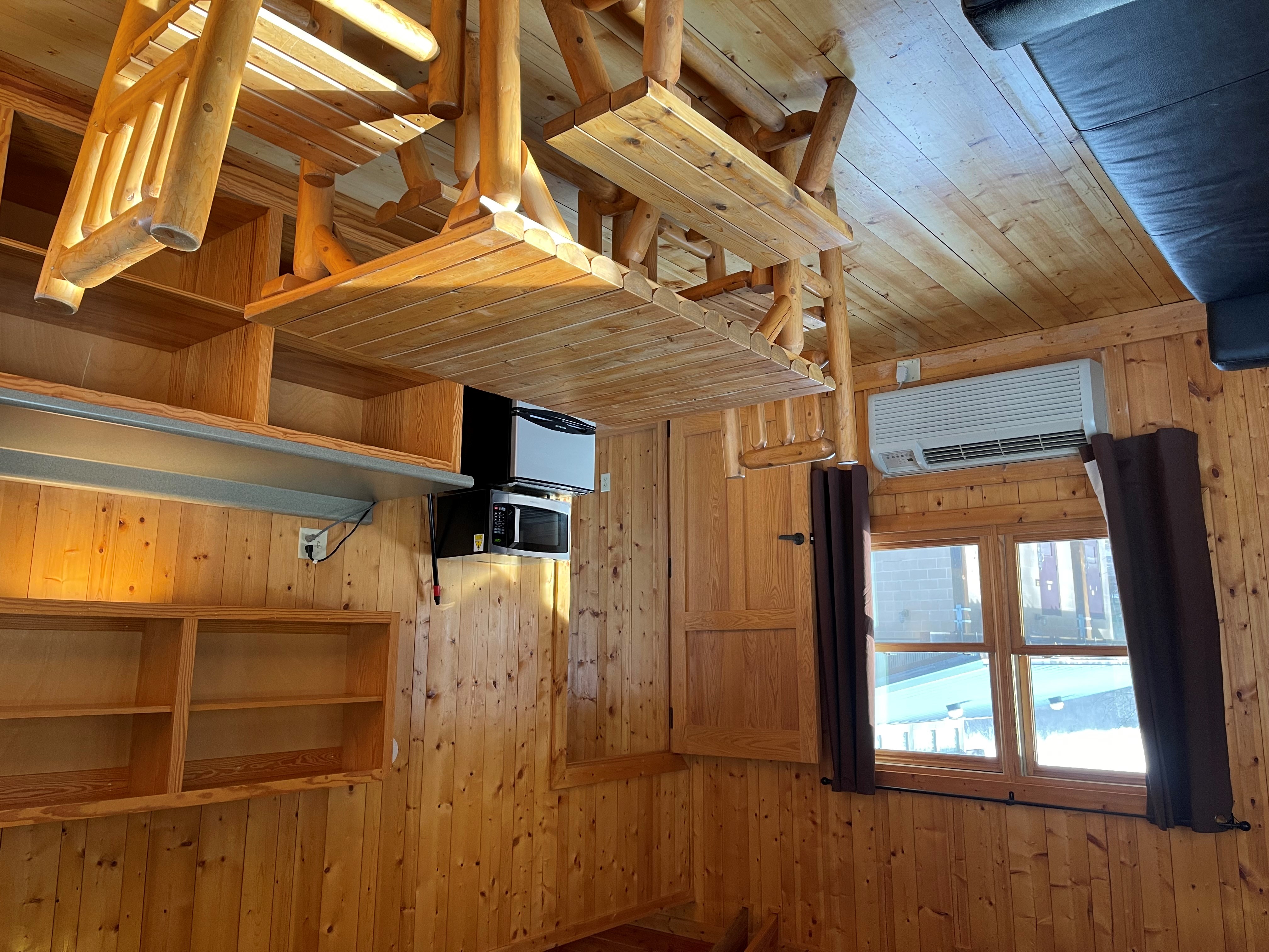 Table, mini fridge, microwave, cupboards and window in cabin