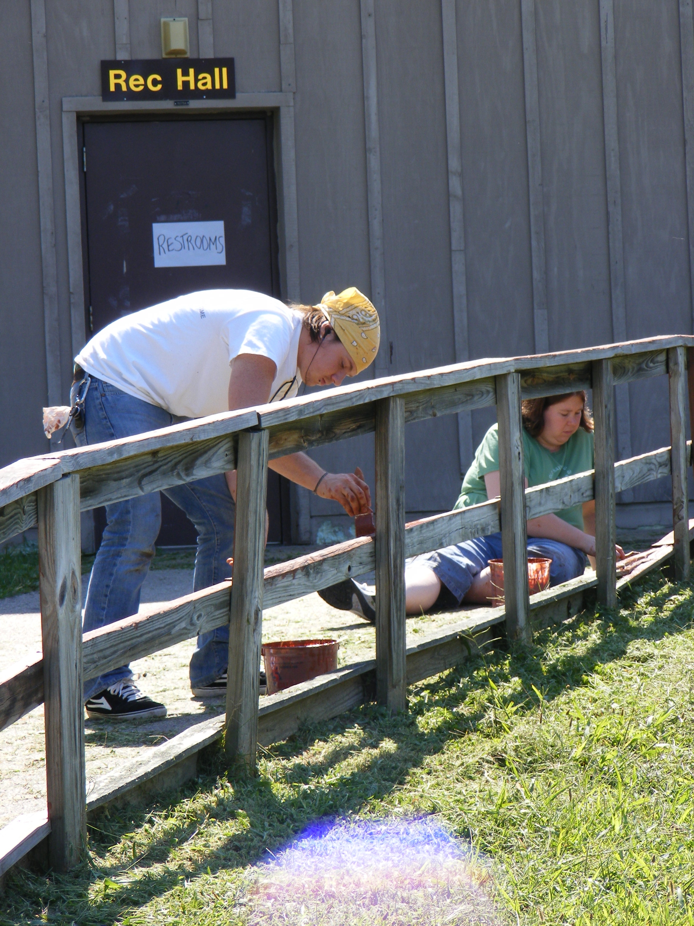two volunteers painting a fence