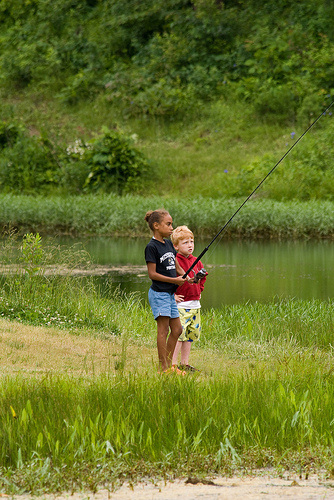 two kids fishing on the bank of the lake