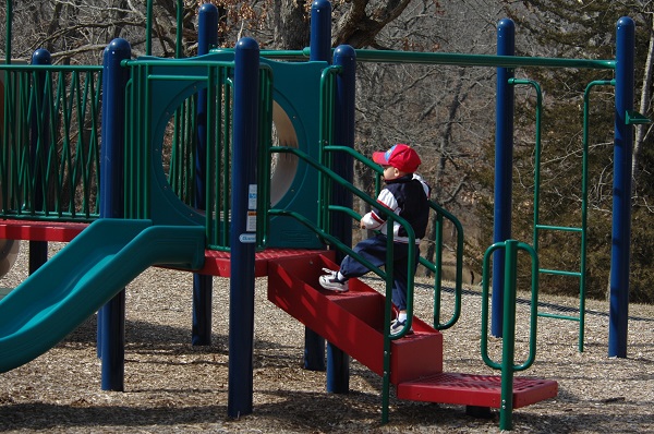 kid playing on playground equipment with slide