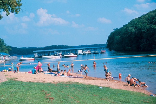People playing and swimming at a beach on a lake