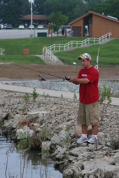 man fishing from lake shore 