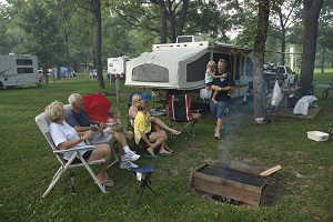 a family sitting around a campfire next to their camper