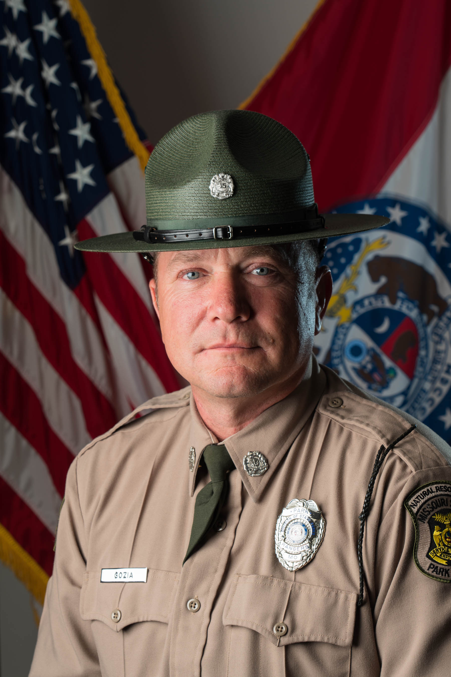 Mike Gozia in hat and uniform with U.S. and Missouri flags and background