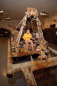 a kid sitting on a piece of the old mining equipment