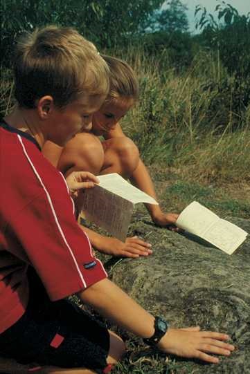 two kids feel the impressions made in some rocks by Osage Indians 