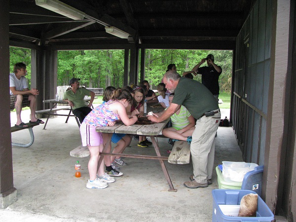 some kids looking at something that the naturalist is showing them 