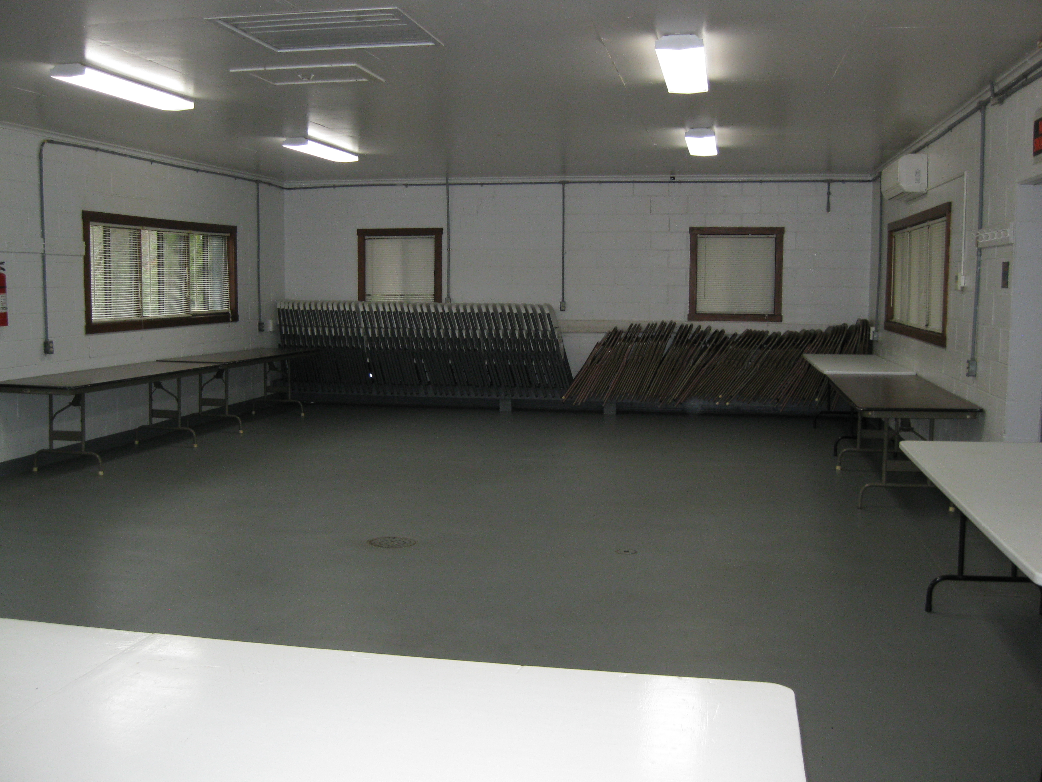 Tables and folding chairs against the walls inside the enclosed shelter