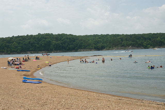 people on the beach and in the lake swimming