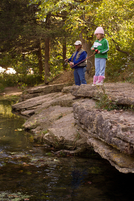 a little girl and a man fishing on the bank