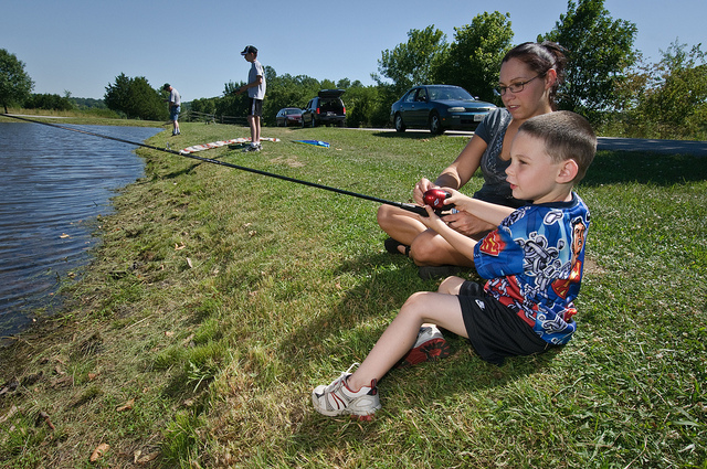 a family sitting on the bank of the river fishing