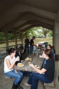 severl people enjoying a meal under one of the picnic shelters