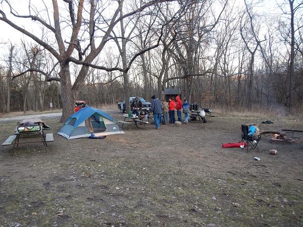 People, a tent and picnic tables in an open area