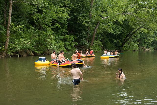 two kids splash in the water while three rafts float by