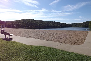 a sidewalk goes along the edge of the beach with a bench