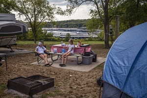 a family sitting at a picnic table by their tent