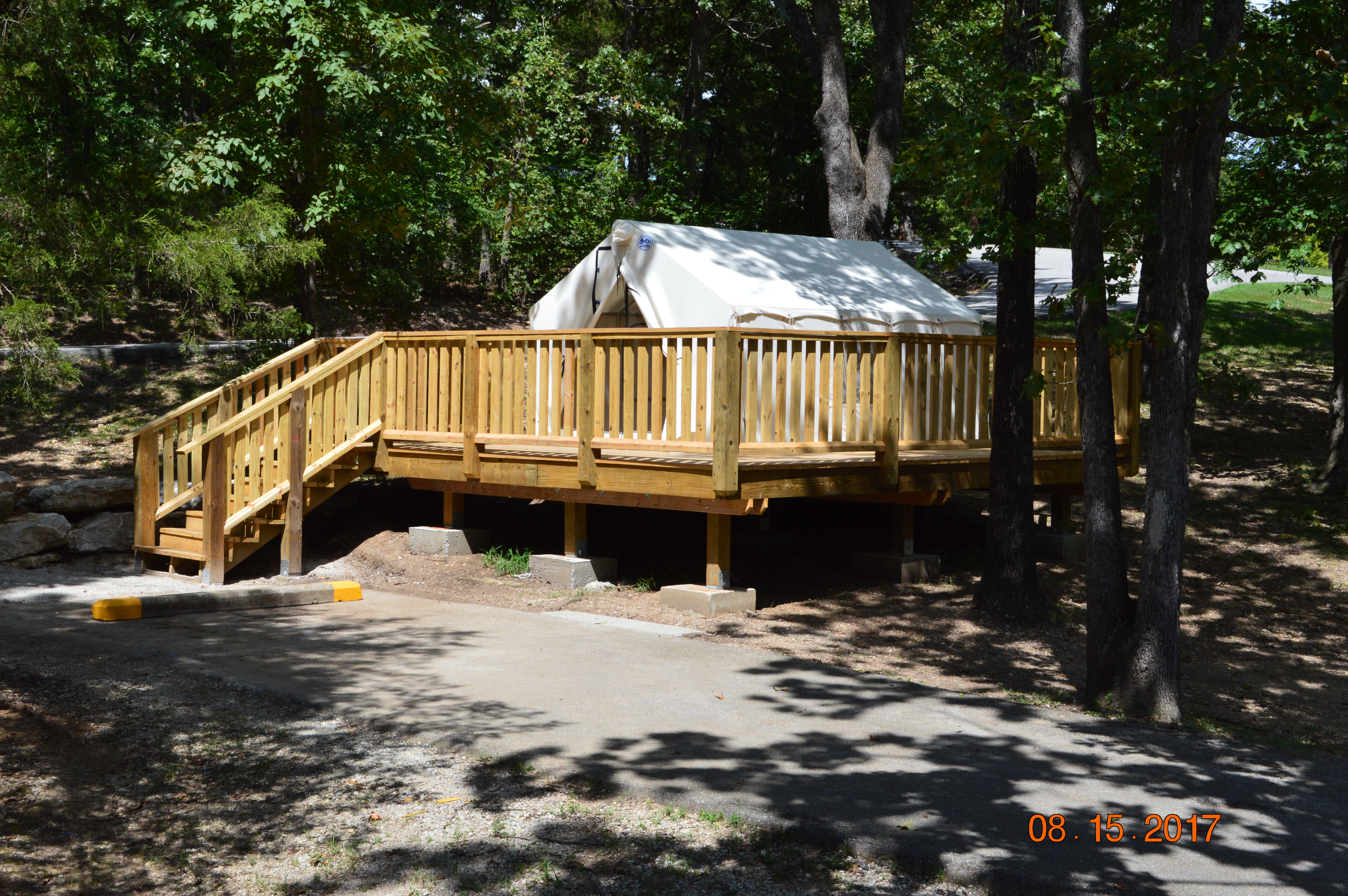 a canvas tent on a wooden platform with steps leading to it