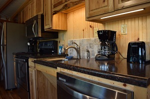 kitchen inside the yurt with microwave, stove, sink and coffee maker