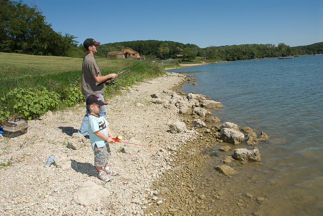 a man and boy fishing from the lake shore