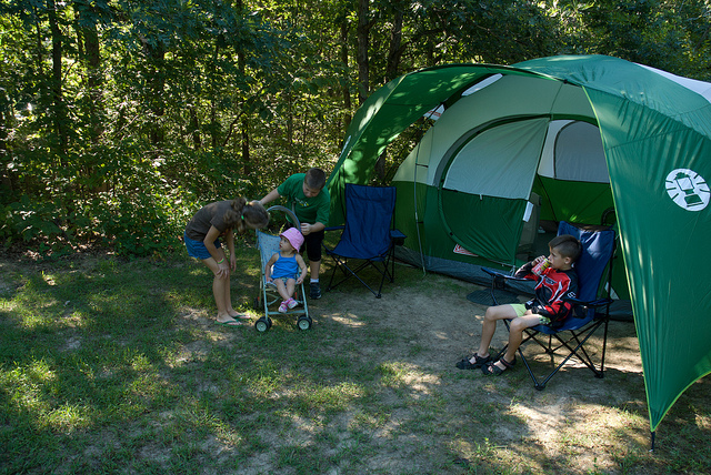 a family sits in lawn chairs outside their tent