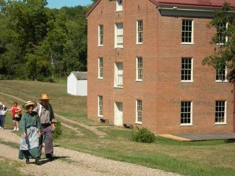 couple in period attire walking in front of the mill