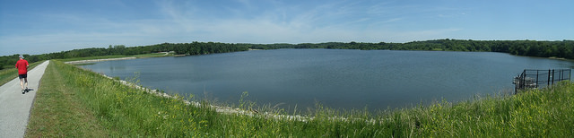 a person jogging on the paved trail next to the lake