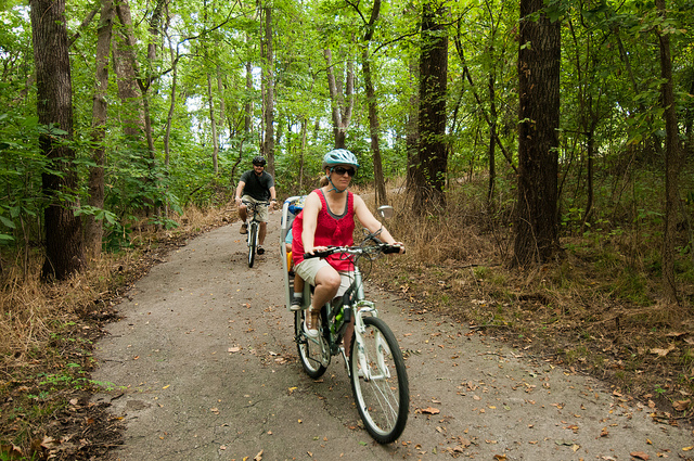 two people riding bikes on the paved trail