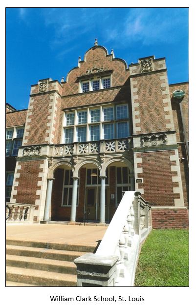 Large brown brick schoolhouse with arched entrances and concrete stairs and leading up to it