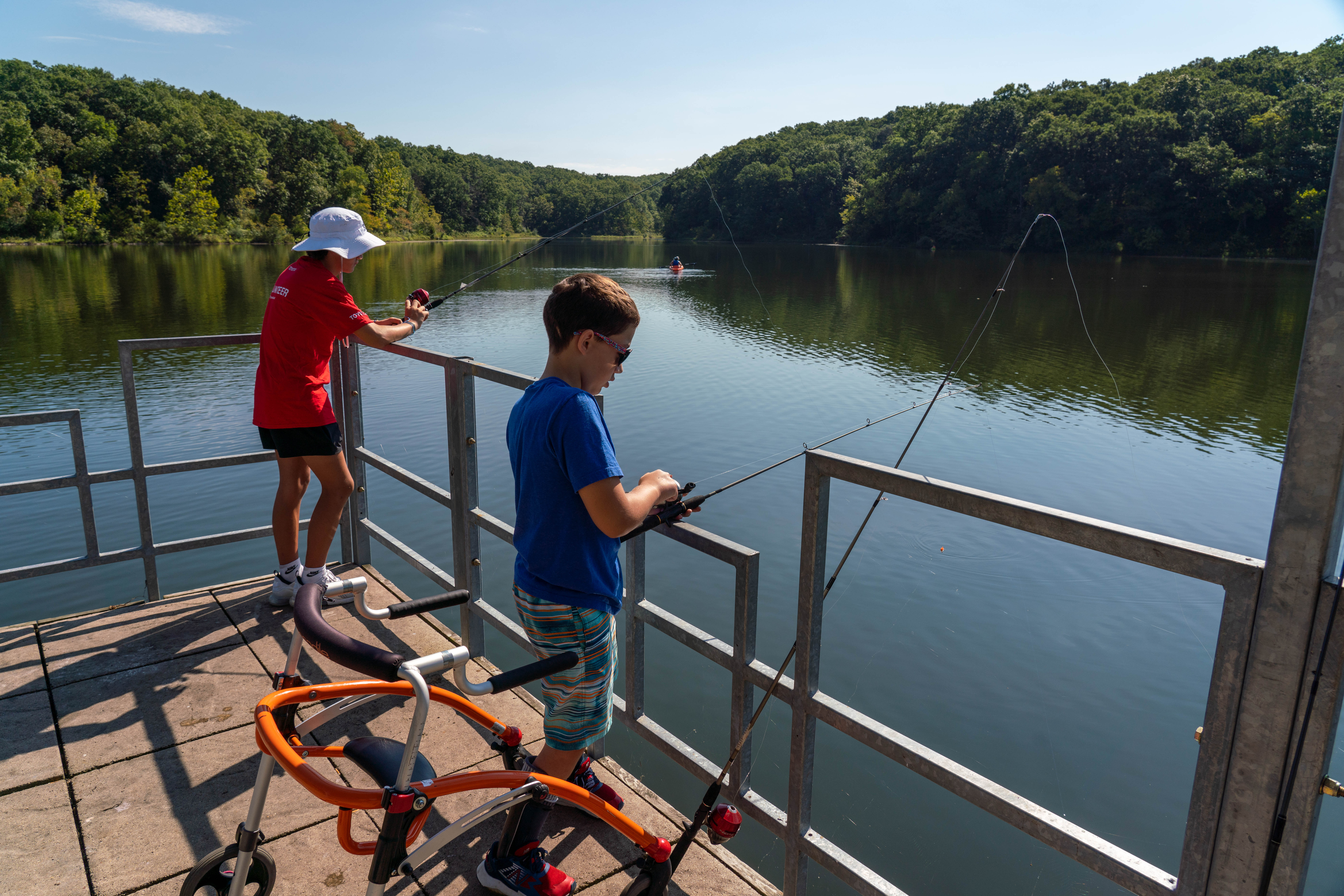 two people fishing into a river off a wooden dock