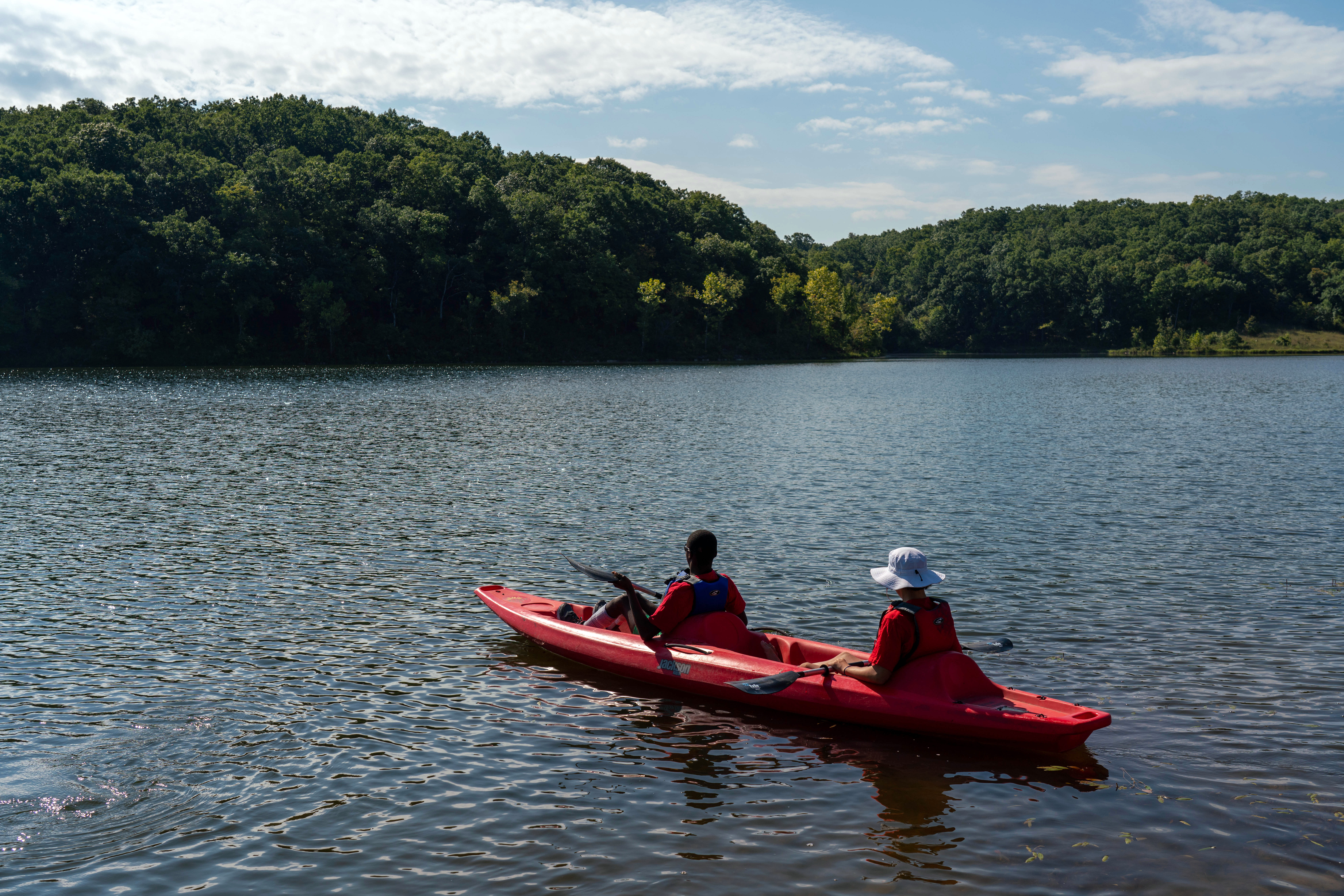 two people kayaking in a red kayak down a river