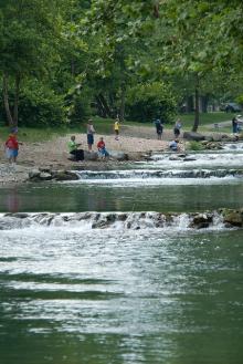 water cascades down the river with people fishing on the bank