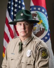 Ranger David Miller standing in-front of a flag