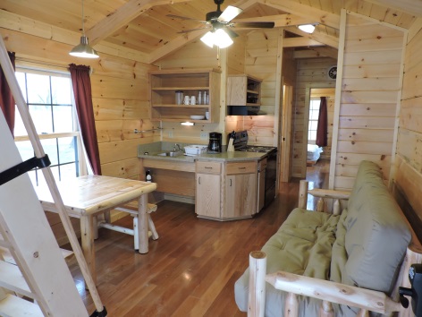 interior of cabin with kitchen area, table and futon