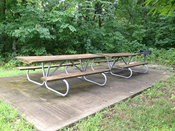 two picnic tables end-to-end on a concrete pad