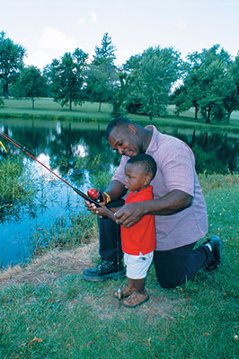 a man helping his toddler son fish